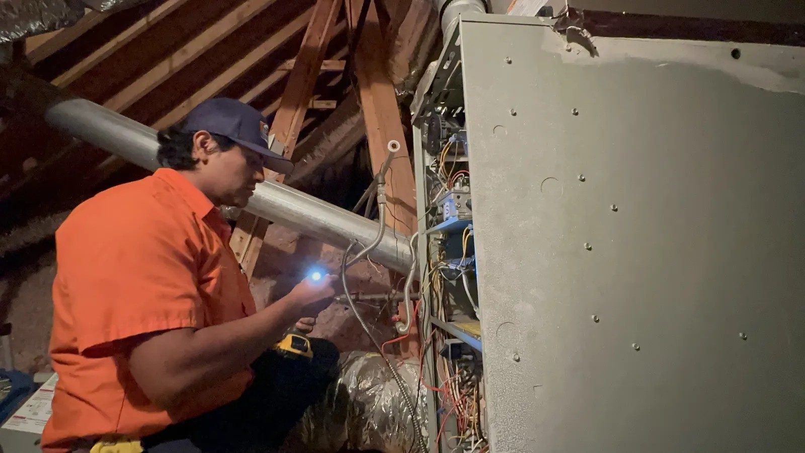 Technician with a flashlight checking an attic furnace