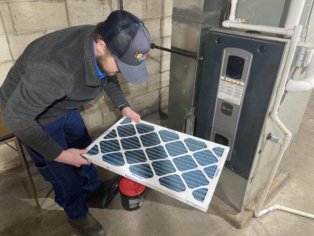 Technician sliding a pleated filter into the return of a furnace