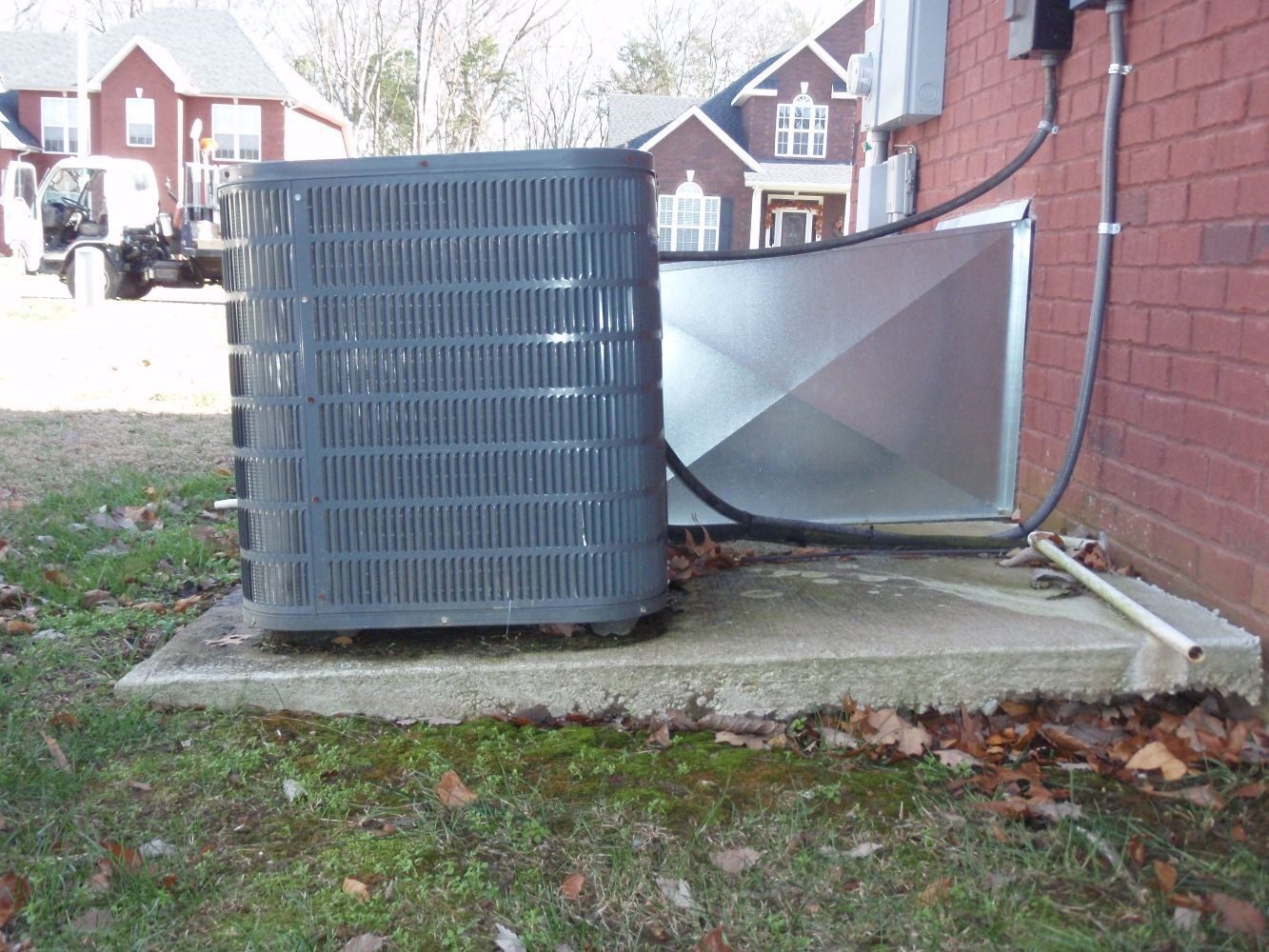 Outdoor air conditioning unit on a concrete pad beside a brick home